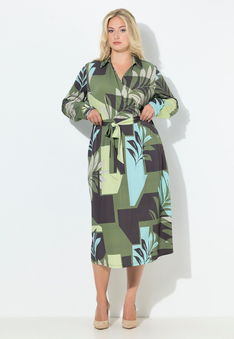Sukienka koszulowa z długim rękawem o abstrakcyjnym wzorze liści w kolorach zielonym, czarnym i niebieskim. Posiada taliowanie z dopasowanym paskiem oraz kołnierzyk.