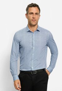 Blauw-wit gestreept shirt met lange mouwen, knoopsluiting, spreadkraag en slanke pasvorm. Gecombineerd met zwarte broek.