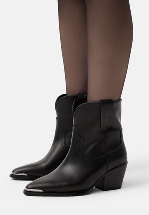 Stivali cowboy neri in pelle, alla caviglia, con punta affusolata e tacco medio a blocco, caratterizzati da cuciture curve e linguette per un facile indossamento.