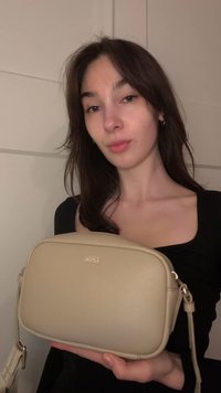 Beige schoudertas met een glad lederen textuur, rechthoekige vorm en subtiele branding. Heeft een afneembare riem en gouden hardware-accenten.