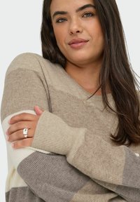 Beige ribbed sweater with v-neck, featuring horizontal stripes in cream and gray, long sleeves with cuff detail, cozy texture.