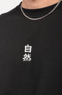 Zwarte sweatshirt met ribbelaccenten bij de hals en witte geborduurde tekst op de voorkant, gemaakt van katoen met een zachte textuur.
