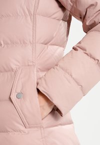 Pink puffer jacket featuring horizontal quilted sections, a side pocket with snap closure, and ribbed cuff details for warmth.