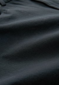 Black fabric with a textured weave, showing ripples and folds. Material appears durable with no distinct patterns or accents.
