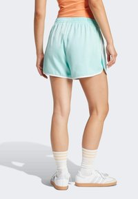 Svijetloplavi atletski šorts s bijelim detaljima, elastičnom trakom u struku, bočnim prorezima, uparen s bijelim tenisicama i prugastim čarapama.