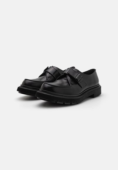 Pantofi din piele neagră cu vârful rotund, design structurat și o talpă groasă, zimțată. Dispun de o curea frontală cu detalii din cataramă.