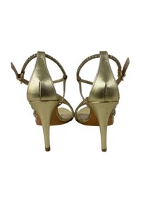 Sandali con tacco dorato e design a strisce, caratterizzati da una fascia alla caviglia posteriore, dettagli in perline trasparenti sulle fasce e tacco a stiletto affusolato.