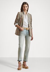Rutet blazer i beige, rosa og grønn over en hvit skjorte, kombinert med lyseblå jeans og beige kilehæler med flettet tekstur.