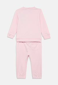 Zachte roze hoodie met lange mouwen en bijpassende broekset voor kinderen, met geribbelde manchetten en een enkele achterzak op de broek.
