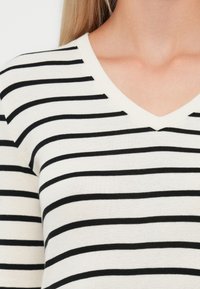 Zwart-wit gestreepte v-hals pullover, met horizontale strepen, een zachte brei textuur en een relaxed fit rondom de halslijn.