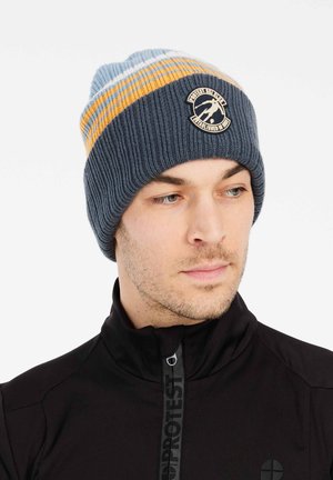 Gorra de punto en azul con rayas naranjas y blancas, con un parche de logo redondo. Textura acanalada y diseño ajustado.