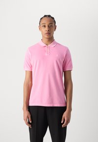 Lys rosa polo skjorte laget av bomull med krage, tre-knaps placket og korte ermer. Har subtil logo brodering.