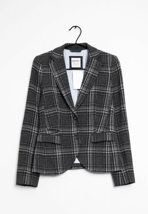Dunkelgrauer Damenblazer mit weißem Karomuster, zwei Knöpfen, Pattentaschen und hellblauem Innenfutter, hängend an einem schwarzen Kleiderbügel.