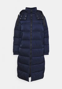 Manteau matelassé bleu marine avec un col montant, fermeture à glissière, boutons-pression sur les épaules et poignets élastiques. Coupe longue, matelassée avec fentes sur les côtés.