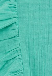 Texturovaná, světle tyrkysová látka s volánky podél jednoho okraje a skládaným designem, s měkkým a vzdušným vzhledem.