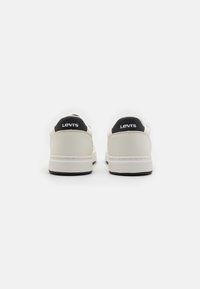 Sneaker bianche con accenti neri sul tallone e sul marchio. Materiale in pelle liscia, forma della punta rotonda e suola in gomma testurizzata.