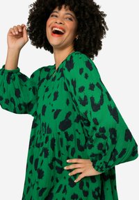 Groene jurk met zwart dierenprint, voorzien van lange pofmouwen en een relaxte pasvorm. Gemaakt van lichtgewicht stof met een gestructureerd oppervlak.