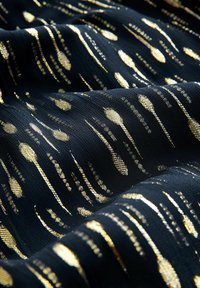 Black textile with a textured surface featuring vertical gold patterns resembling elongated shapes, creating a dynamic visual contrast.