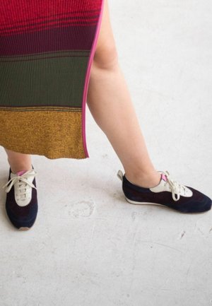 Sneakers in suede con un design bicolore in blu navy e crema, con chiusura lace-up, dettagli a contrasto e superficie texture.