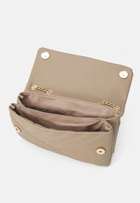 Borsa a tracolla beige trapuntata con dettagli in oro. Il design compatto presenta un scomparto principale e una tasca più piccola, foderati in morbido tessuto.