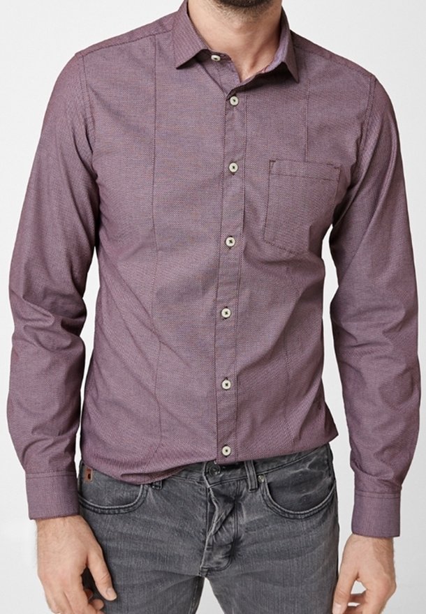 Långärmad skjorta i ett blandat lila tyg. Har en knapp-ned krage, bröstficka och strukturerat mönster. Knapparna är ljusa.