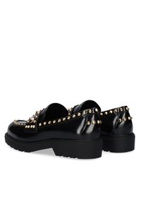 Zapatos de charol negro con puntas redondeadas, con tachuelas doradas a lo largo de la parte superior y la parte trasera. Suelas gruesas de goma negra texturizada.