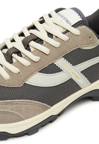 Grau-beige Sneaker mit einem Obermaterial aus Mesh, Wildlederakzenten und cremefarbenen Schnürsenkeln. Enthält das kontrastierende Markenlogo und eine schwarze Gummisohle.