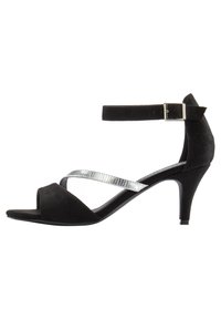 Sandalia de tacón alto de ante negro con una correa texturizada plateada, puntera abierta y hebilla ajustable en el tobillo. Diseño de tacón curvado con una suela lisa.