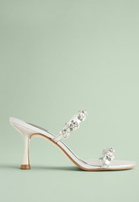 Silverfärgade sandaler med klack och blommor som dekoration på remmarna, öppen tå-design, elegant silhuett och avsmalnande klack med en gyllene accent.