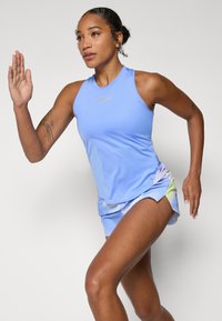 Camiseta deportiva azul clara con un logo reflectante, combinada con pantalones cortos multicolores que presentan un diseño degradado. Adecuada para correr.