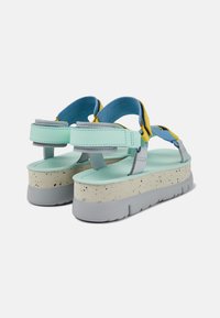 Sandali platform colorati con cinturini verde menta, accenti gialli, suole grigie e una base texturizzata maculata.
