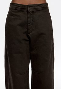 Pantalones de pierna ancha en marrón oscuro, hechos de algodón, que presentan una textura suave, bolsillos frontales y costuras cosidas, con un diseño de cintura alta.
