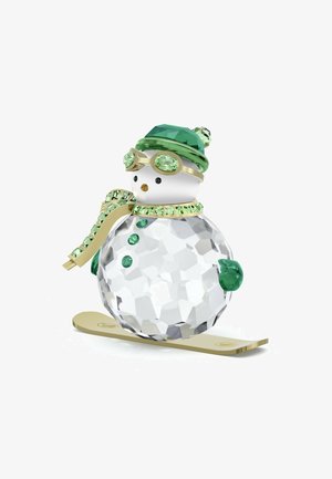 Kristallen sneeuwpopfiguur op een gouden ski, met groene accenten, een groene hoed, skibril en een sjaal versierd met lichtgroene edelstenen.