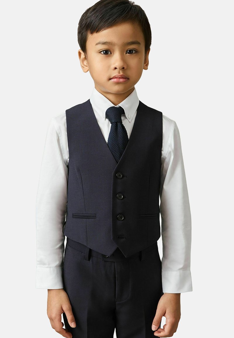 Gilet e pantaloni blu navy con camicia bianca, dotati di quattro bottoni, rever a punta e cravatta scura a trama. Tessuto con superficie liscia.