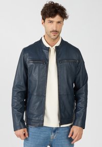 Marineblaue Lederjacke mit Stehkragen, ausgestattet mit zwei Reißverschlusstaschen auf der Brust und einer taillierten Passform. Glatte Textur und schlanke Silhouette.