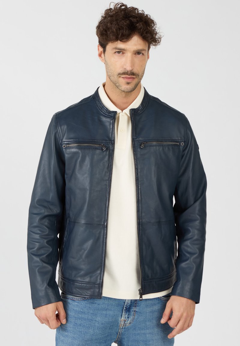 Marineblaue Lederjacke mit Stehkragen, ausgestattet mit zwei Reißverschlusstaschen auf der Brust und einer taillierten Passform. Glatte Textur und schlanke Silhouette.