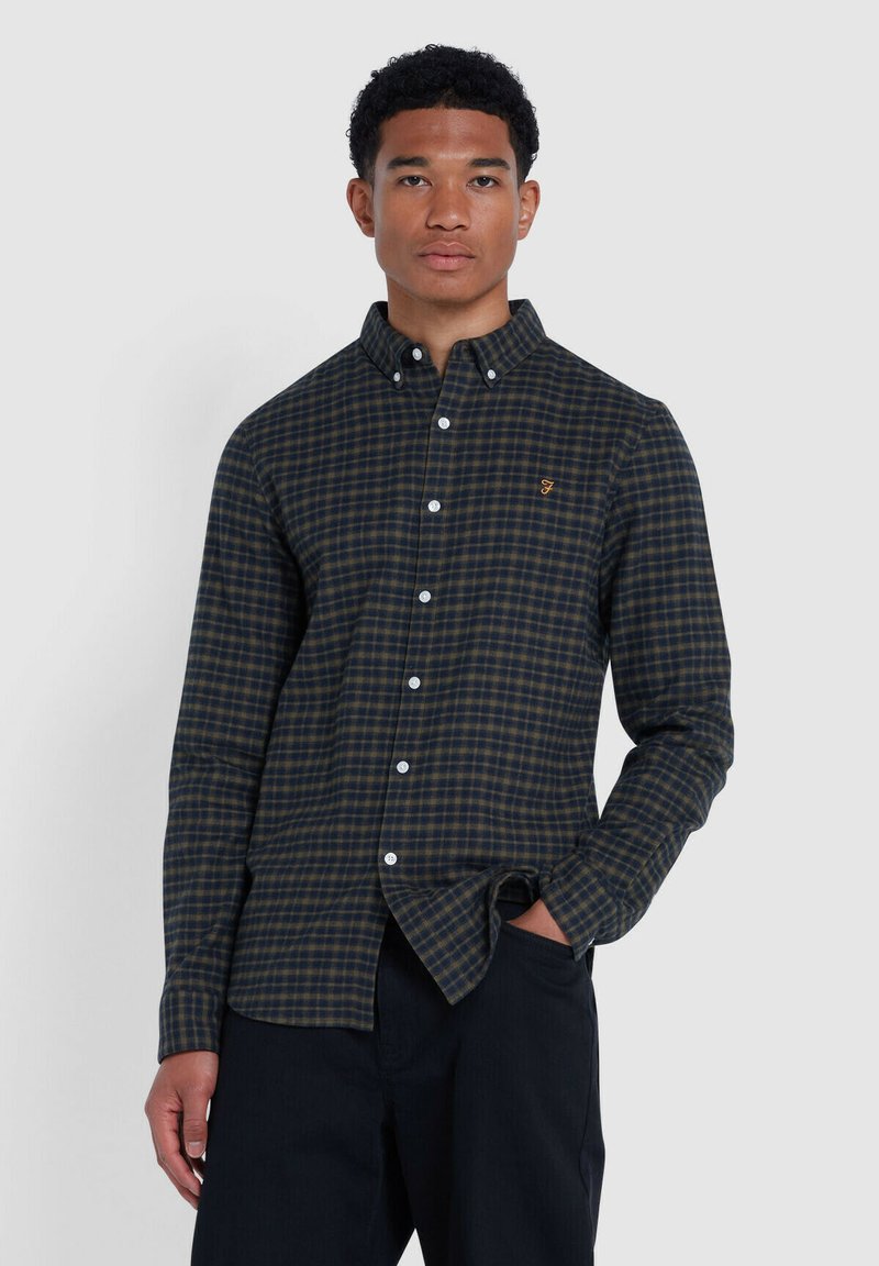 Chemise à manches longues à carreaux bleu marine et vert avec col boutonné, dotée de boutons blancs et d'un petit logo brodé sur la poitrine.