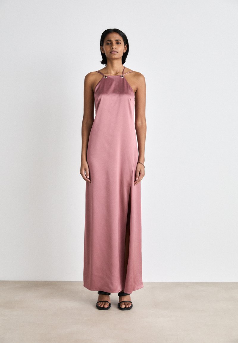 Rochie maxi din satin moale de culoare roz deschis, cu o fenta, curele subțiri și accente metalice la decolteu. Textură netedă, design până la podea.