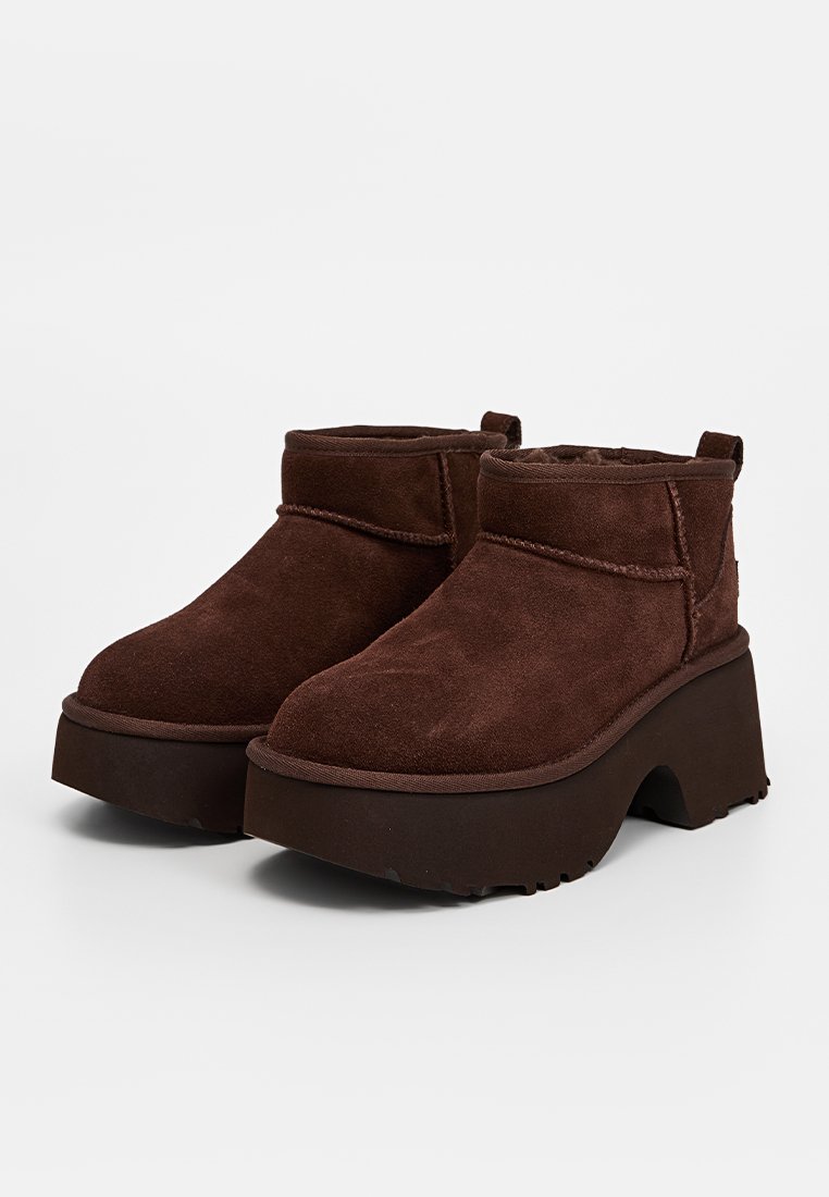 Bottines en cuir suédé marron avec un bout rond, un intérieur douillet et une semelle plateforme épaisse et légèrement incurvée. Accents de couture minimalistes sur les côtés.