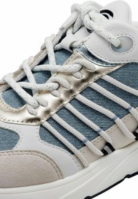 Baskets avec une tige en denim et en cuir blanc ornée d'accents métalliques. Lacets blancs épais et semelle en caoutchouc. Panneau latéral texturé gris.