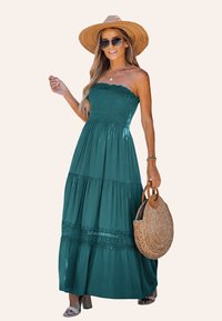 Teal, gelaagde maxi-jurk met gesmokte buste, kantafwerking aan de zoom en een gevlochten strooien tas. Gestyled met trendy zonnebril en chunky héélsandalen.