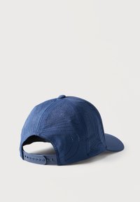 Μπλε ρυθμιζόμενο καπέλο του μπέιζμπολ με διάτρητα στροβιλιασμένα σχέδια στα υφασμάτινα μέρη, εμφανιζόμενο από το πίσω μέρος σε λευκή επιφάνεια.