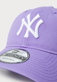 Purple baseball cap with white "NY" logo, adjustable strap, and a circular tag displaying "9TWENTY" on the front. Smooth fabric texture.