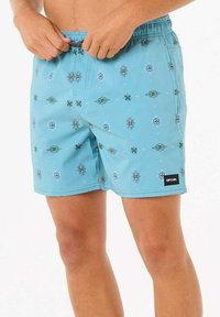 Shorts de bain bleus avec un motif géométrique en vert et blanc, taille élastique et étiquette logo noire sur le côté gauche.