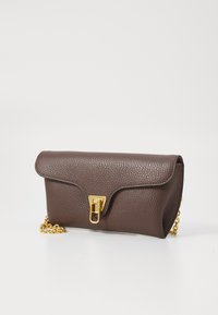 Pochette en cuir texturé marron avec un rabat incurvé, fermoir en métal doré et une chaîne dorée. Forme compacte au design minimaliste.