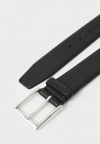 Correa de reloj de cuero negro con hebilla rectangular plateada. Presenta una textura suave, punta afilada y múltiples agujeros de ajuste.