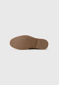 Suela de zapato de goma marrón con superficie texturizada, forma redondeada y detalles mínimos, diseñada para tracción y durabilidad.