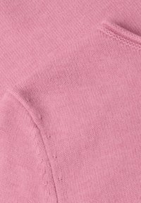 Gros plan d'un tissu tricoté rose doux montrant des coutures détaillées et une texture lisse.