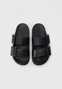 Sandali neri con due cinghie a fibbia, realizzati in materiale liscio e resistente, dotati di una soletta contornata e di un design minimalista.