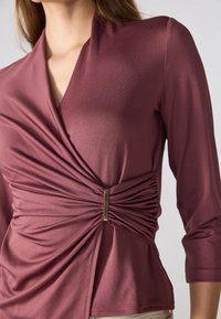 Marjaana käärevälis alakate, kolmene kvartalide hõlmadega, millel on kokkutõmbunud kangas ja keskel kuldne aktsent. Sile ja kerge materjal.